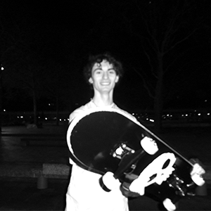 photo en noir et blanc d'un jeune homme avec un skate et un tshirt tête de mort