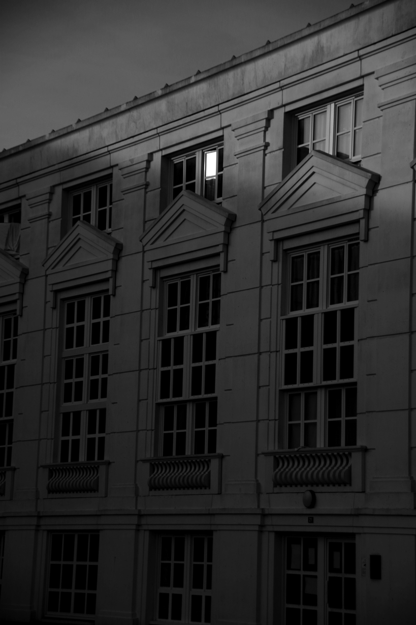 photo en noir et bloanc d'un immeuble cergyssois, une fenêtre très lumineuse se distinguant des autres